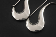 Close view of polished sterling silver crescent earrings showing smooth reflective moon curves.