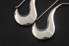 Close view of polished sterling silver crescent earrings showing smooth reflective moon curves.