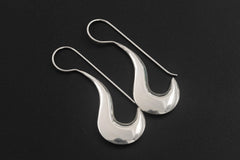 Lunar Crescent Silver Drop Earrings displayed on dark background with elongated French hook wires.