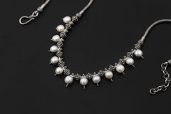 Pearl necklace shown on sand with natural white Pearls and detailed sterling silver bead elements.