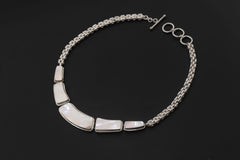 Mother of Pearl necklace shown in hand with five polished shell panels and sterling silver chain.