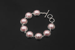 Pink Mabe Pearl bracelet displayed on dark background with round Pearls and sterling silver toggle clasp.