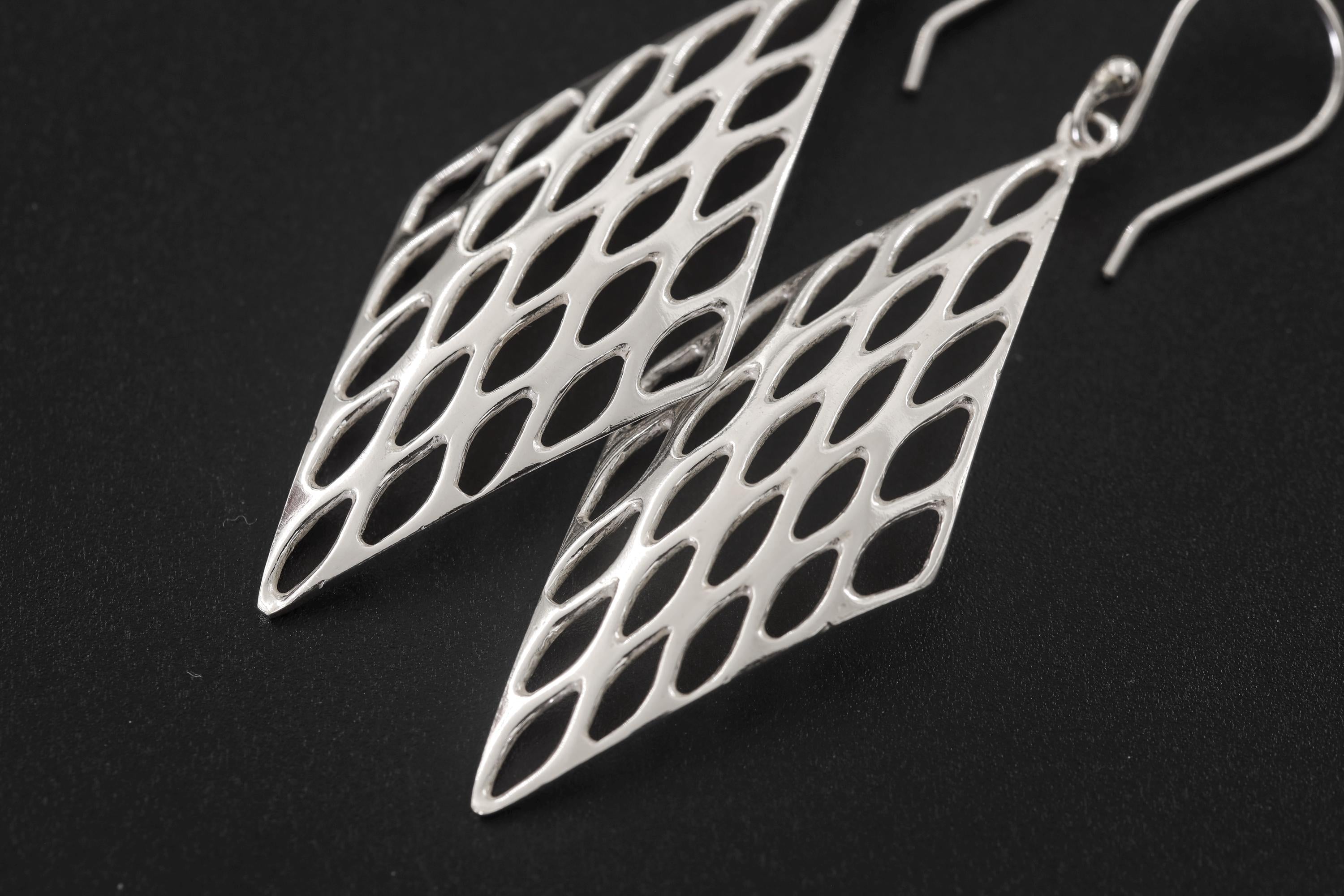 Close view of sterling silver geometric earrings showing polished open lattice pattern and hook fittings.