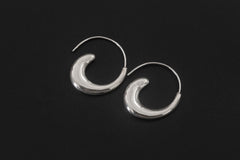 Lunar Tide Wave Earrings displayed on dark background with sculptural crescent silver form.