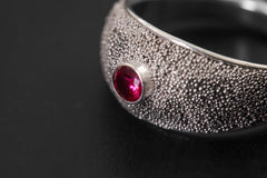 Close view of textured Garnet ring showing red faceted stone set in oxidized sterling silver.