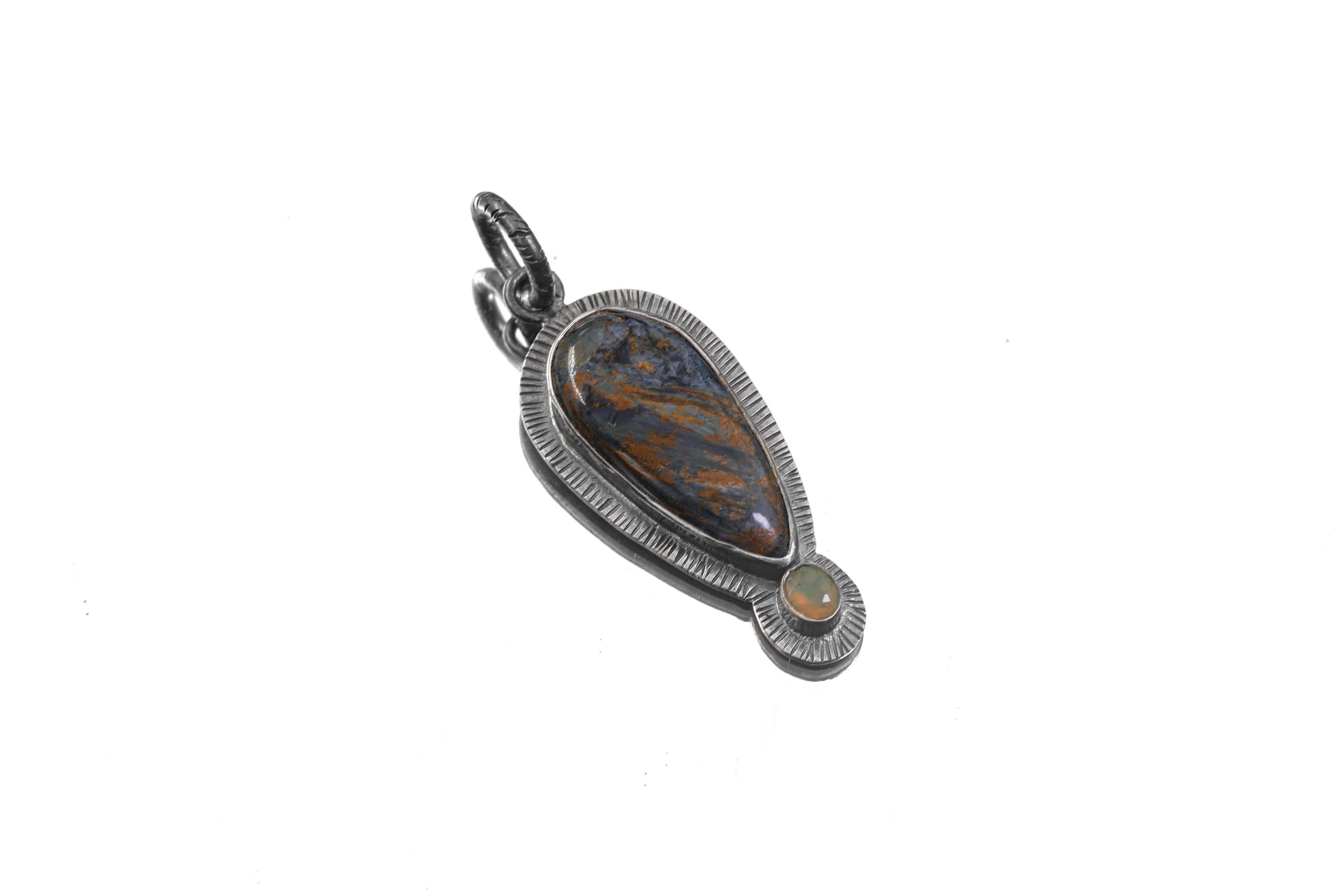 Pietersite Ethiopian Opal sunburst pendant shown on white background with textured sterling silver setting.