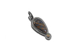Pietersite Ethiopian Opal sunburst pendant shown on white background with textured sterling silver setting.