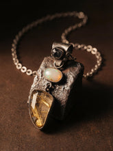 Sapphire Opal and Golden Rutile Quartz pendant shown on dark stone with oxidized sterling silver chain.