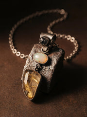 Sapphire Opal and Golden Rutile Quartz pendant shown on dark stone with oxidized sterling silver chain.