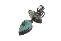 Double Turquoise pendant displayed on white background with sculptural silver bail and blue-green matrix stones.