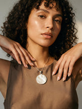 Mother of Pearl round disc pendant shown worn on model as a luminous sterling silver shell necklace.