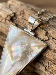 Close view of Mother of Pearl triangle pendant showing iridescent shell surface in polished silver bezel.