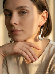 Sterling silver crescent earrings shown worn on model as minimalist polished moon drop earrings.