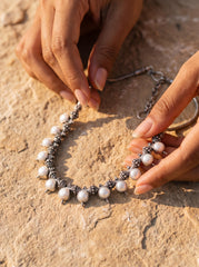 Pearl necklace shown on sand with natural white Pearls and detailed sterling silver bead elements.