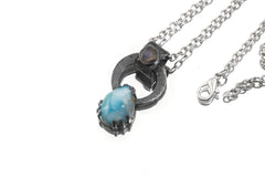 Larimar and Blue Moonstone pendant shown with silver chain, highlighting handmade oxidized silver and blue gemstone contrast.