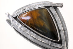Close-up of Tiger Eye triangle pendant showing golden chatoyancy and handmade oxidized silver sun details.