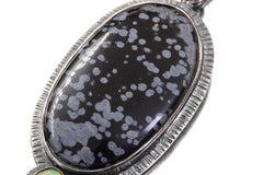 Close-up of Dalmatian Jasper pendant showing spotted black and grey patterning in textured sterling silver frame.