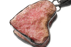 Close-up of Rhodochrosite pendant showing pink stone texture and handmade sterling silver edge.