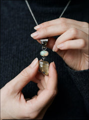 Multi-stone pendant shown held in hand with Sapphire, Opal, Rutile Quartz, and oxidized silver setting.