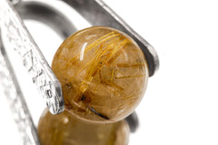 Close view of Golden Rutilated Quartz sphere with rutile needles inside silver spinner setting.