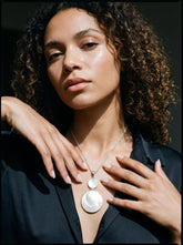 Mother of Pearl double disc sterling silver pendant shown worn on model as a luminous shell necklace.