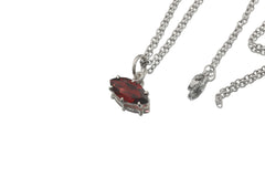Garnet marquise pendant displayed on dark slate with sterling silver chain and red gemstone glow.