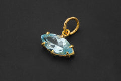 Close view of faceted Blue Topaz pendant showing sky-blue stone in gold-plated claw setting.