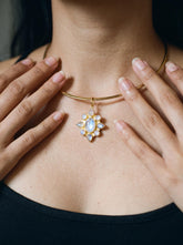Blue Moonstone flower pendant in 18k gold-plated sterling silver, shown worn on a necklace with soft lunar gemstone glow.