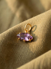 Amethyst eye pendant displayed on warm fabric with gold-plated sterling silver and violet marquise stone.