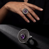 Amethyst disc ring shown worn on hand with bold textured sterling silver face and violet cabochon.