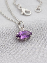Faceted Amethyst marquise pendant shown on linen with sterling silver claw setting.