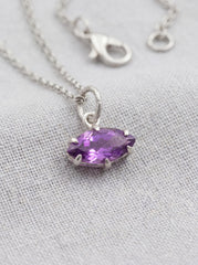 Faceted Amethyst marquise pendant shown on linen with sterling silver claw setting.