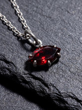 Oxidized sterling silver Garnet marquise pendant shown on dark slate with deep red gemstone.