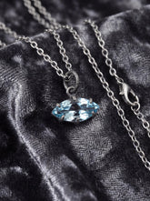 Blue Topaz eye pendant shown on dark fabric with oxidized sterling silver chain and pale blue marquise stone.