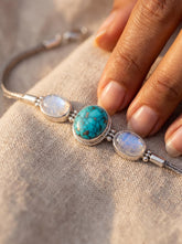 Turquoise and Moonstone sterling silver bracelet shown worn on model with ocean-blue centre stone.