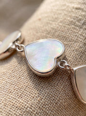 Close view of Mother of Pearl heart bracelet showing creamy nacre shimmer in polished silver setting.