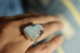 Handmade 925 sterling silver Larimar ring shown worn on the hand, with freeform ocean-blue stone and hammered band.