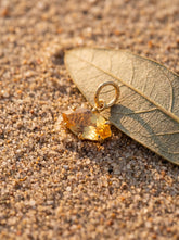 Citrine eye pendant displayed on sand with gold-plated sterling silver and marquise yellow gemstone.