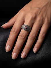 Garnet signet ring shown worn on hand with broad textured sterling silver band.
