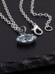 Blue Topaz eye pendant displayed on dark slate with oxidized chain and textured silver setting.