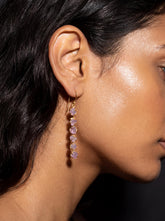 Raw Amethyst cascade earrings shown worn on the ear, with 18k gold-plated sterling silver and long purple crystal dangles.
