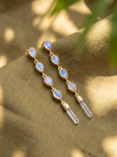 Blue Moonstone and Clear Quartz gold-plated sterling silver cascade earrings shown worn on the ear with long crystal drops.