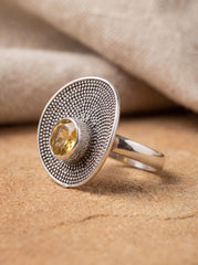 Citrine disc ring displayed on sand with polished sterling silver and golden faceted centre stone.