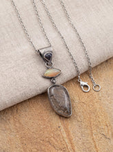 Opal Sapphire and Black Rutile Quartz pendant displayed on fabric with oxidized sterling silver chain.