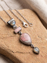 Moonstone Labradorite Rhodochrosite pendant in oxidized 925 sterling silver shown on natural fabric with chain detail.