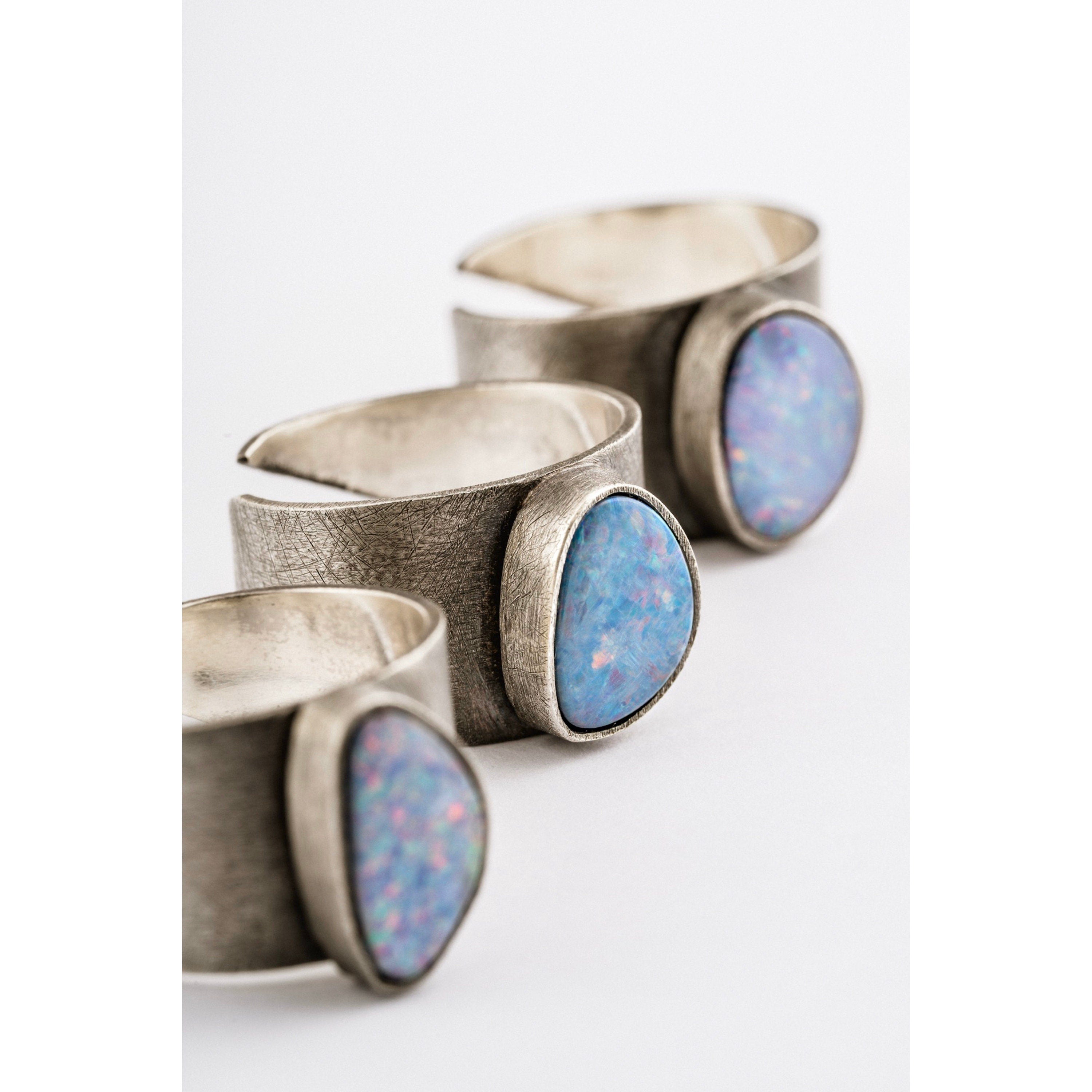 Oxidized Opal Doublet Adjustable Ring shown on white background with textured sterling silver band and colourful Opal stones.