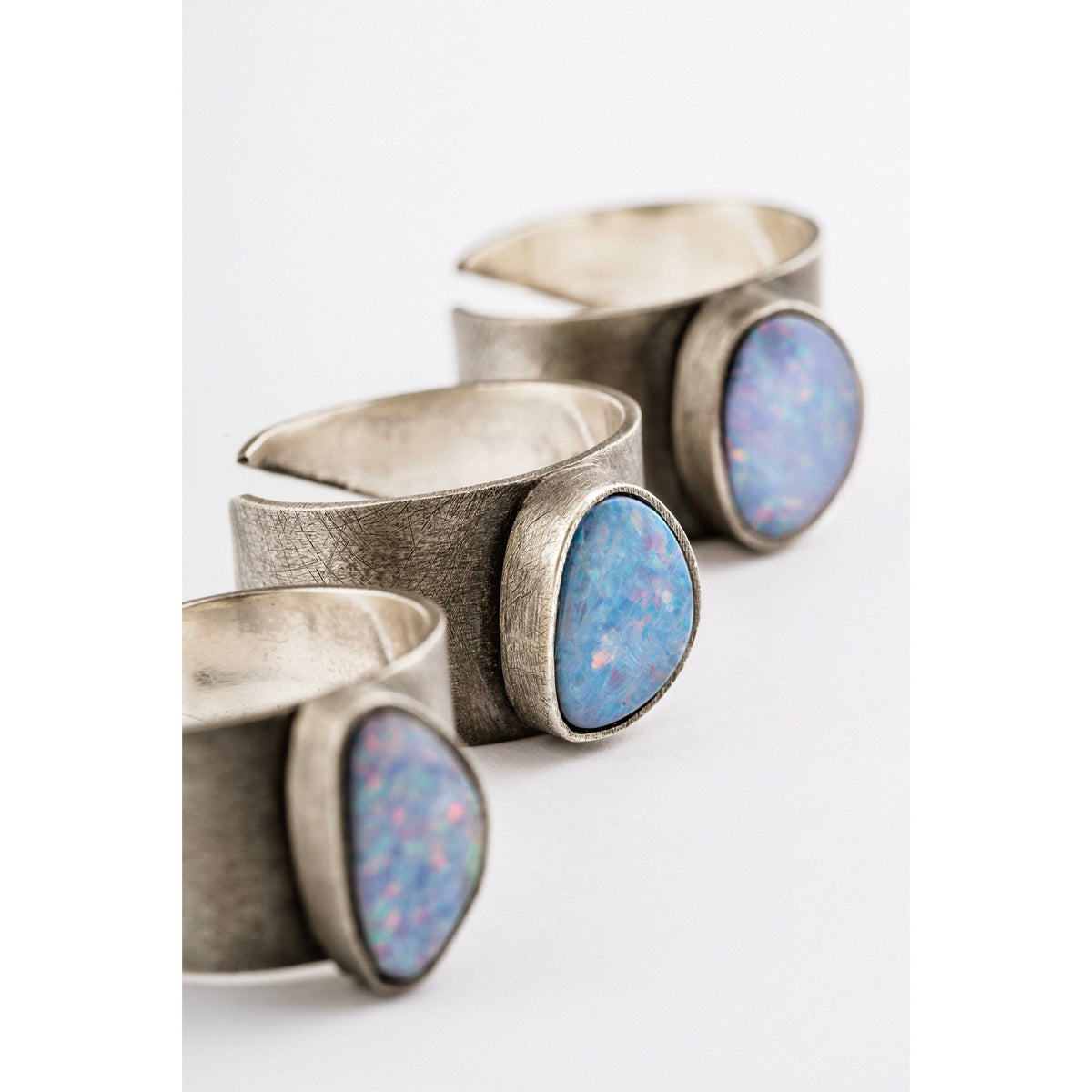 Oxidized Opal Doublet Adjustable Ring shown on white background with textured sterling silver band and colourful Opal stones.