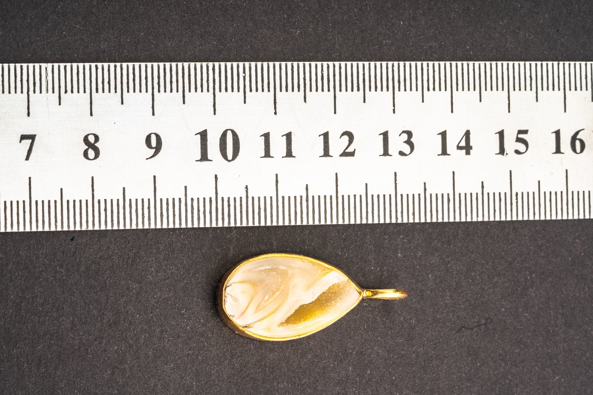 Seashell pendant shown beside a ruler for scale with gold-plated sterling silver bail and hammered bezel.
