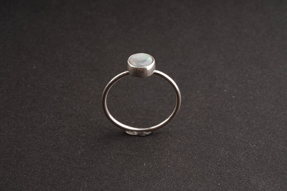 Lightning Ridge Black Opal sterling silver ring shown on a dark background, with rough opal face and delicate round band.