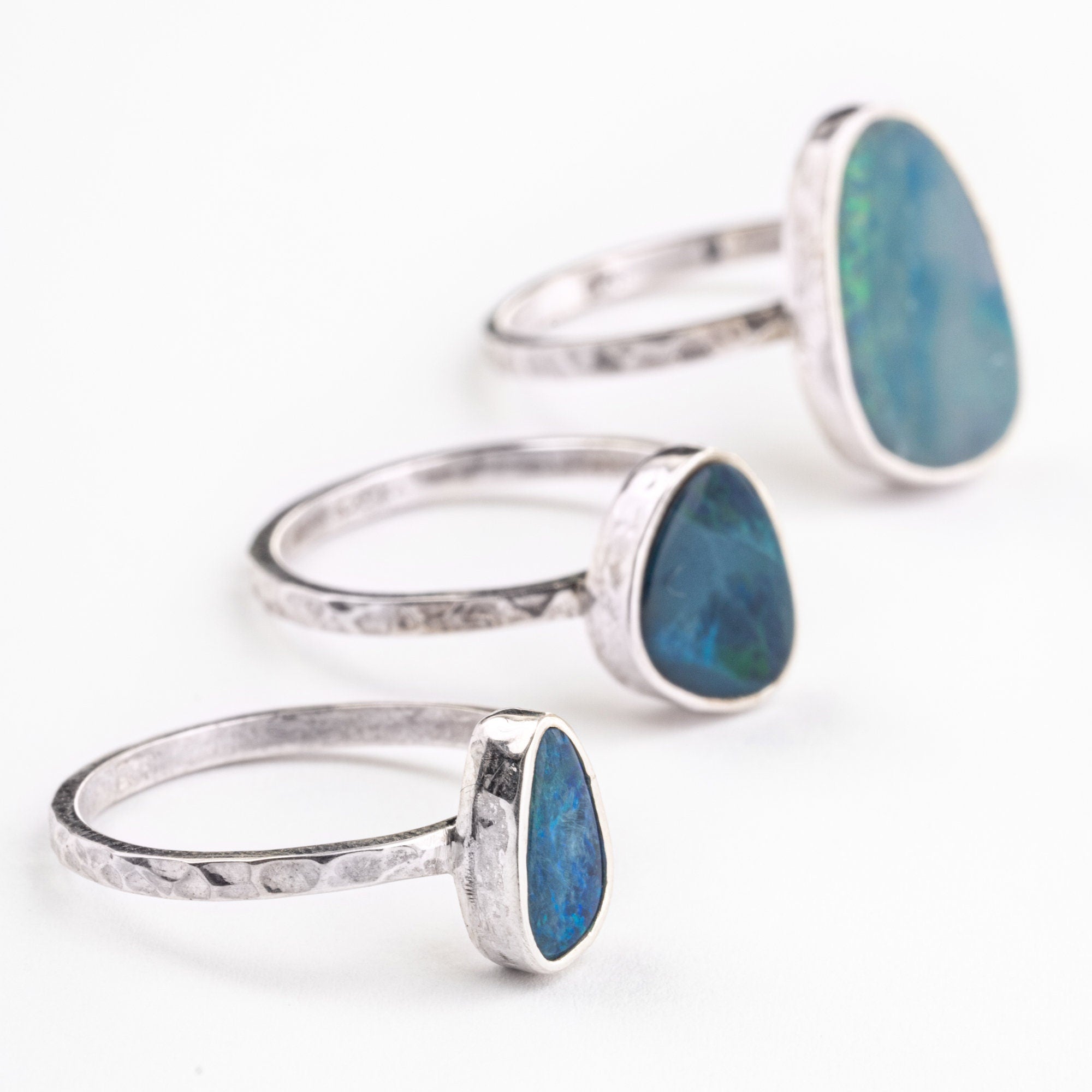 Precious Australian Opal Doublet Rings shown on white background with textured silver bands and luminous Opal stones.